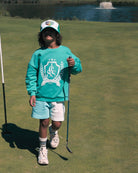 Boy model wearing the Happy Human Cap with the Country Club Sweater in Spruce Green and the Jog Shorts in Colour Block.