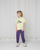 Boy model wearing the T-Shirt in colour Lime Cream with caption Ciao in dark purple from the frontside.