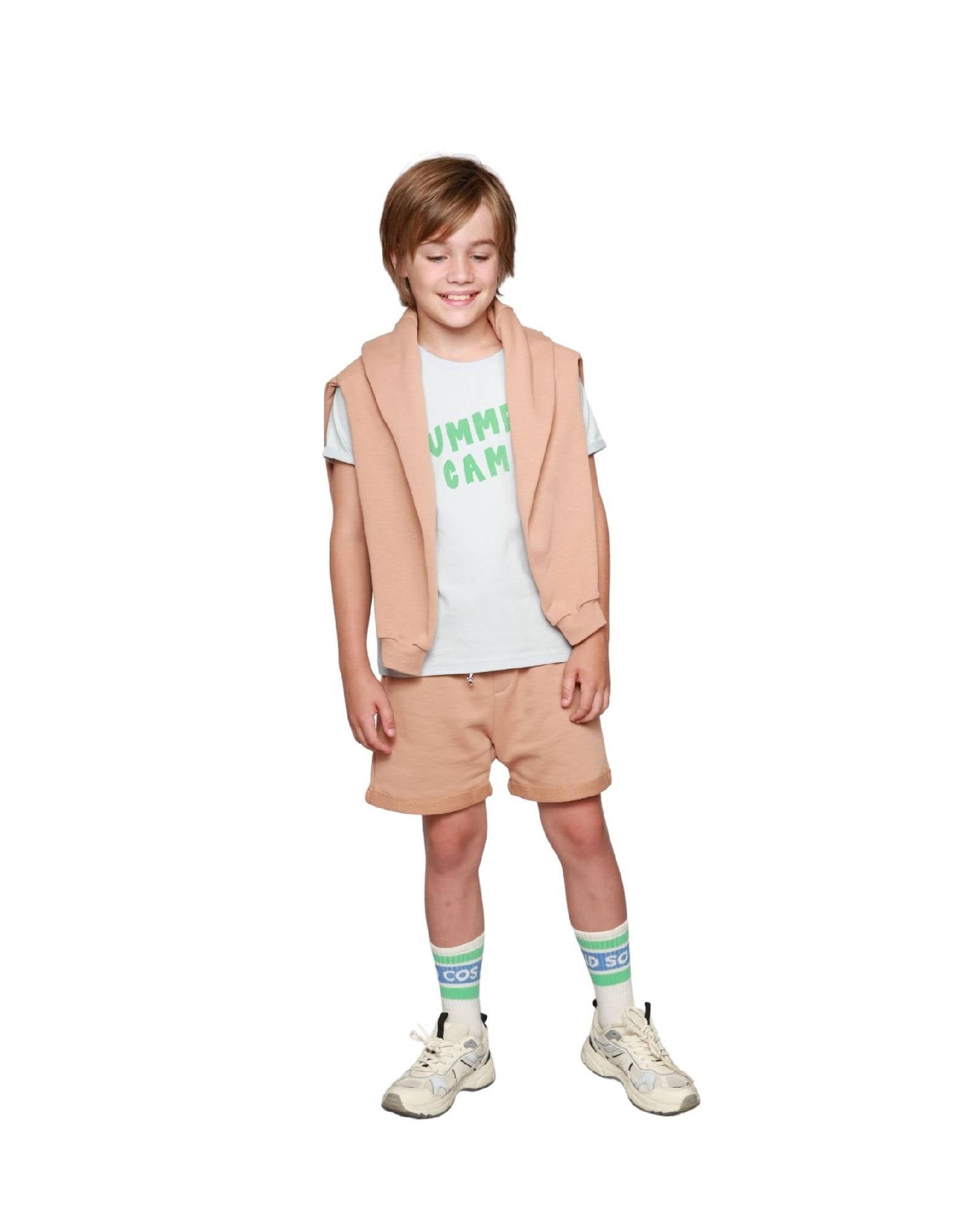 Boy model wearing Jog Shorts Praline with T-shirt Summer Camp and the matching Sweater Happy Human in Praline.