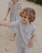 Boy model wearing the Charlie Shirt in Striped Beige White, combined with the Julian Shorts in Striped Beige White Seersucker. Twinning Girl model is wearing the River Dress in Striped Beige White Seersucker.