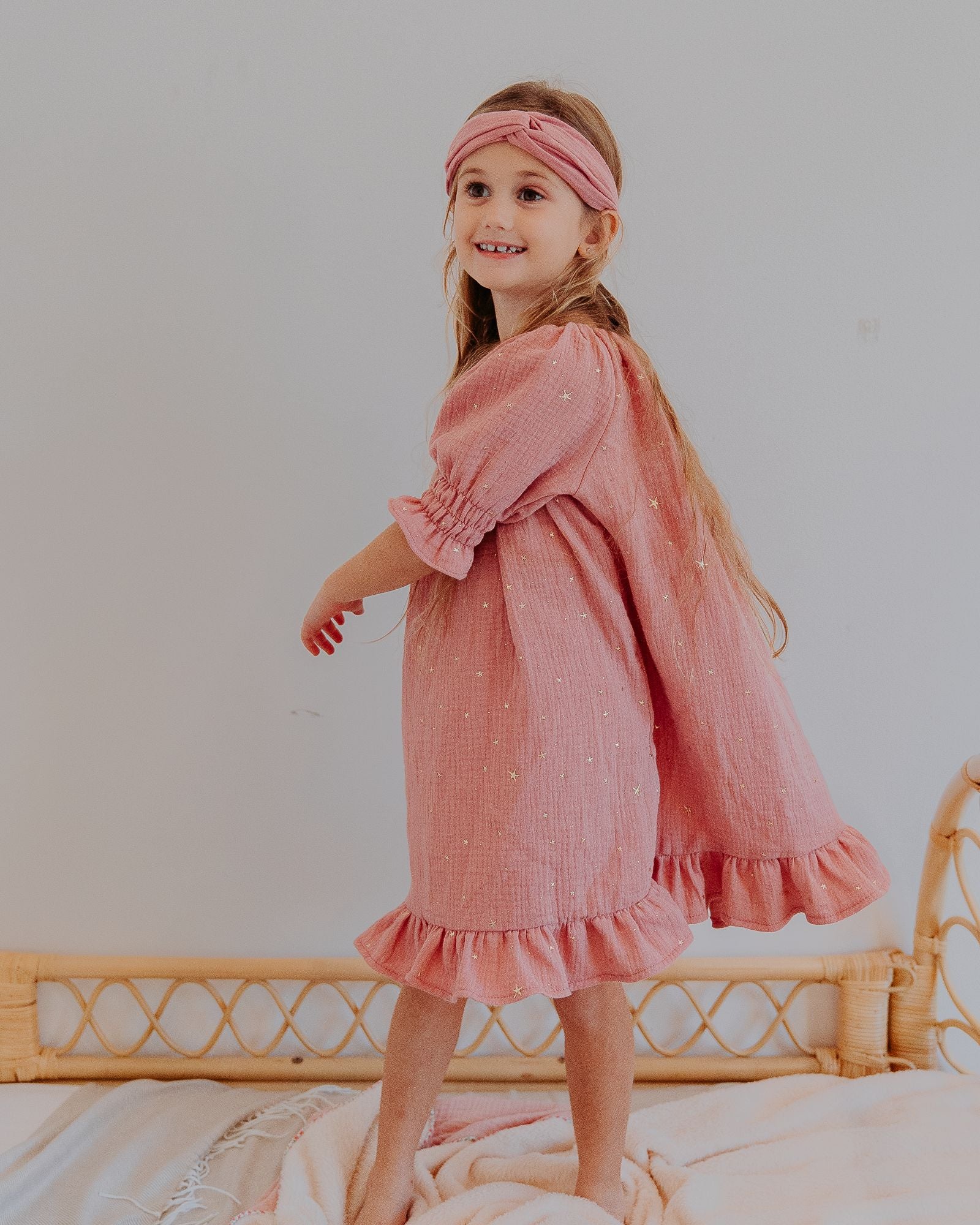 Girl model wearing the Alexa Dress in Rose Pink with Golden Drop Stars, combined with the Twisted Headband in Blush Pink.