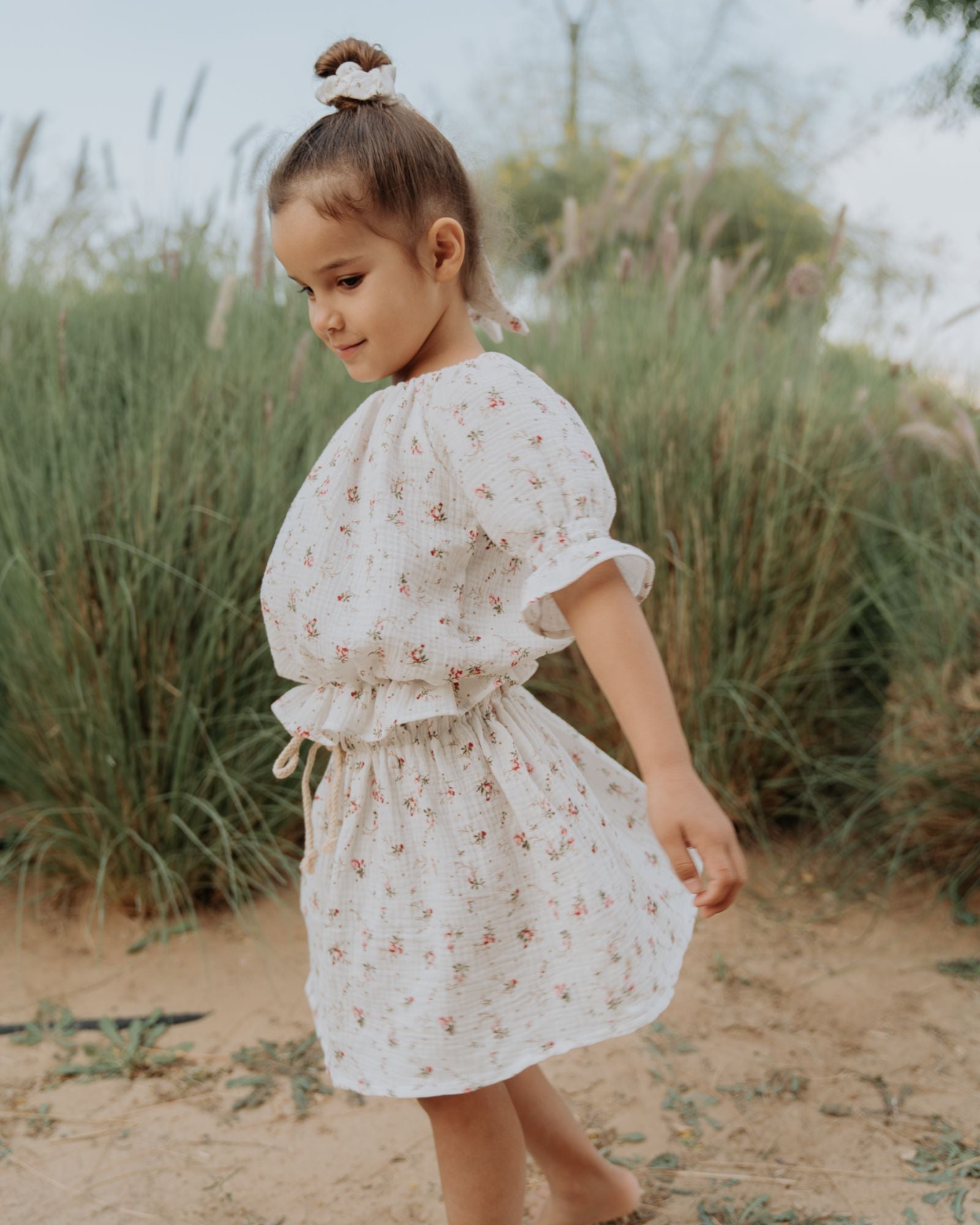 Girl model wearing the Alexa Top in Wildflower, matching the Sienna Skirt in Wildflower and the Scrunchie Long in Wildflower. All come in the fabric Muslin Cotton.