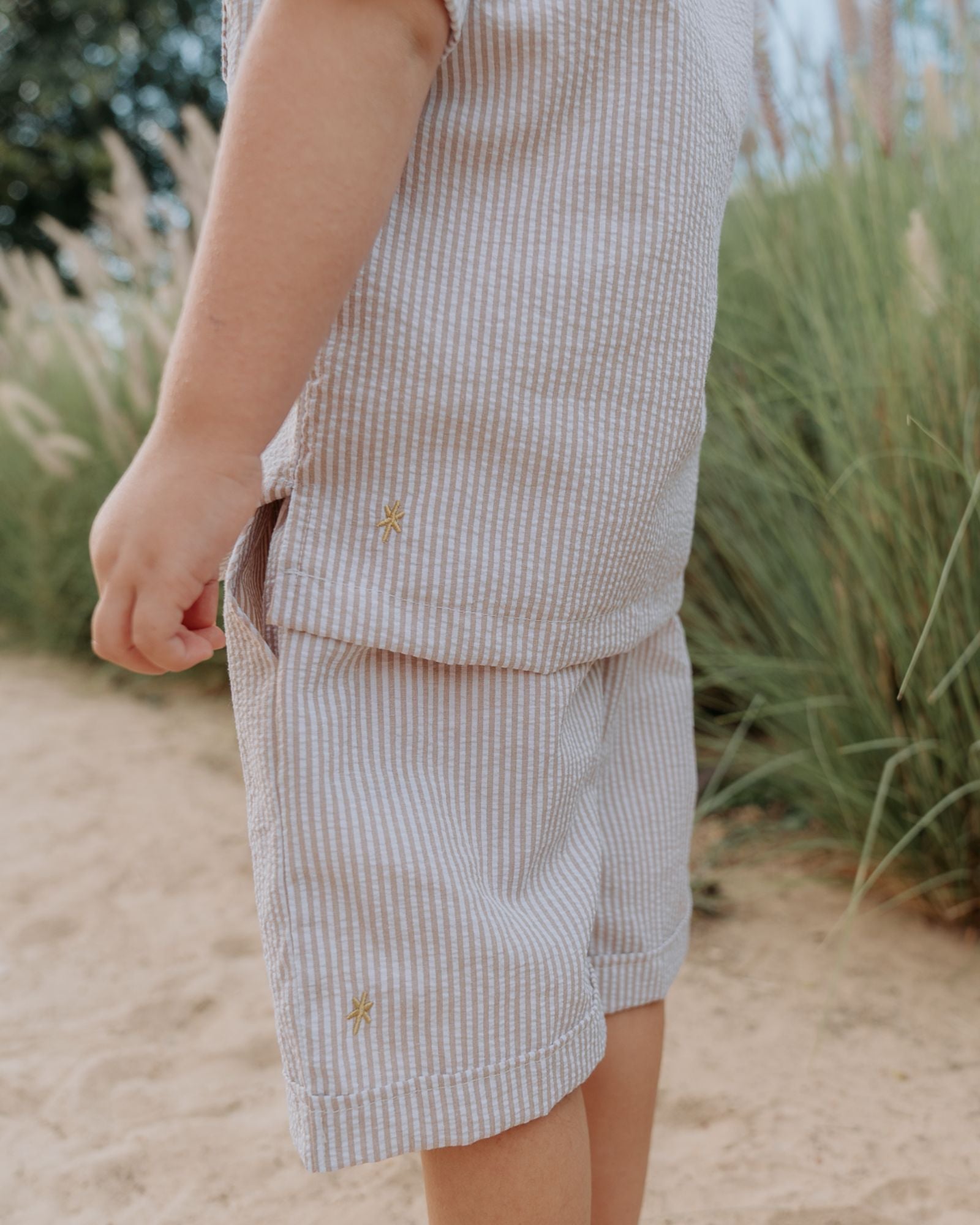 Boy model wearing the Charlie Shirt in Stripes Beige White byLes Vedettes, with the matching Julian Shorts.